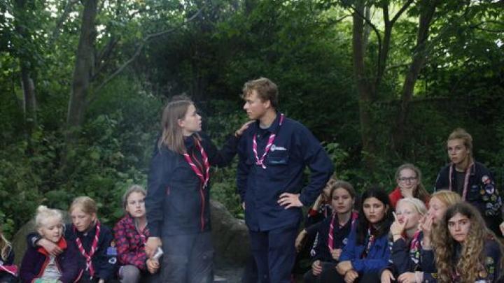 Billedet viser to spejderledere omgivet af en flok glade spejdere